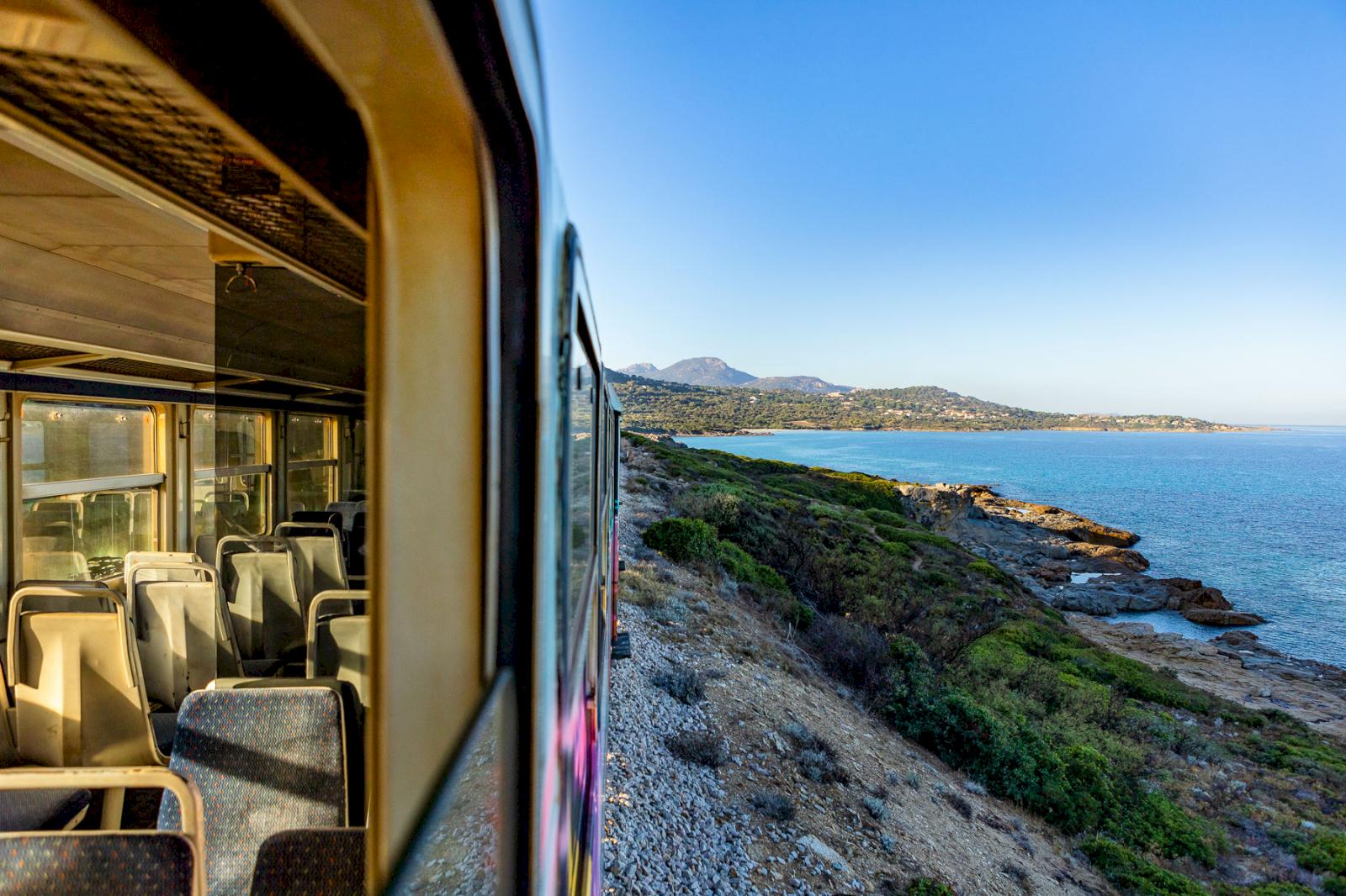 Tåg som kör längs kusten på ön Korsika 