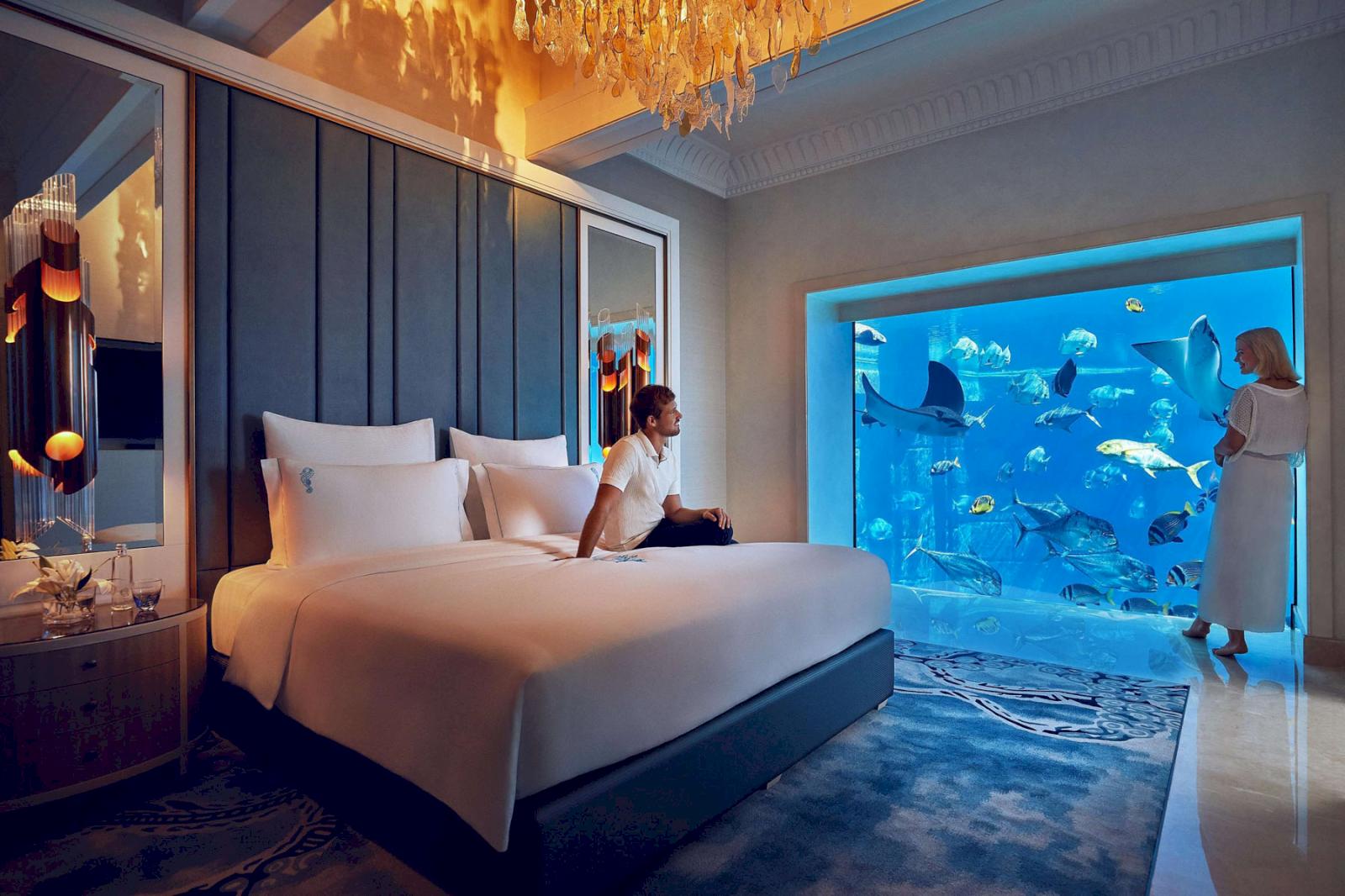 Hotellrum under vattnet med fiskar utanför fönstret. 