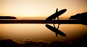Surfare i solnedgång.