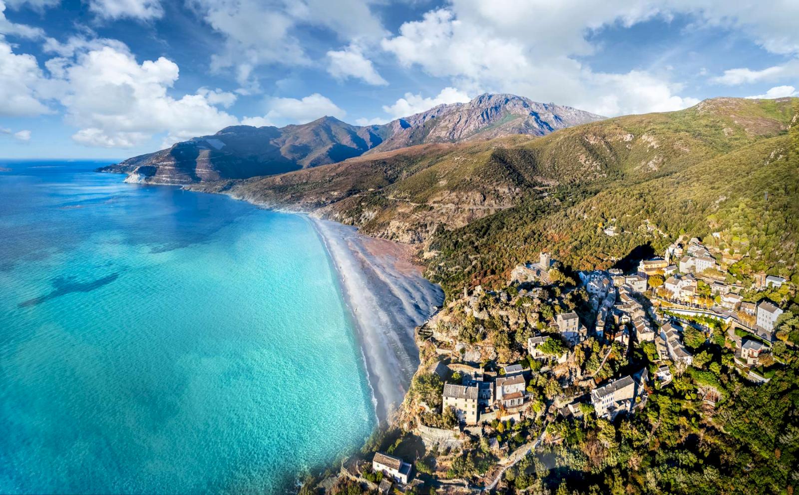 Turkost hav, vit strand och berg på Cap Corse, Korsika. 