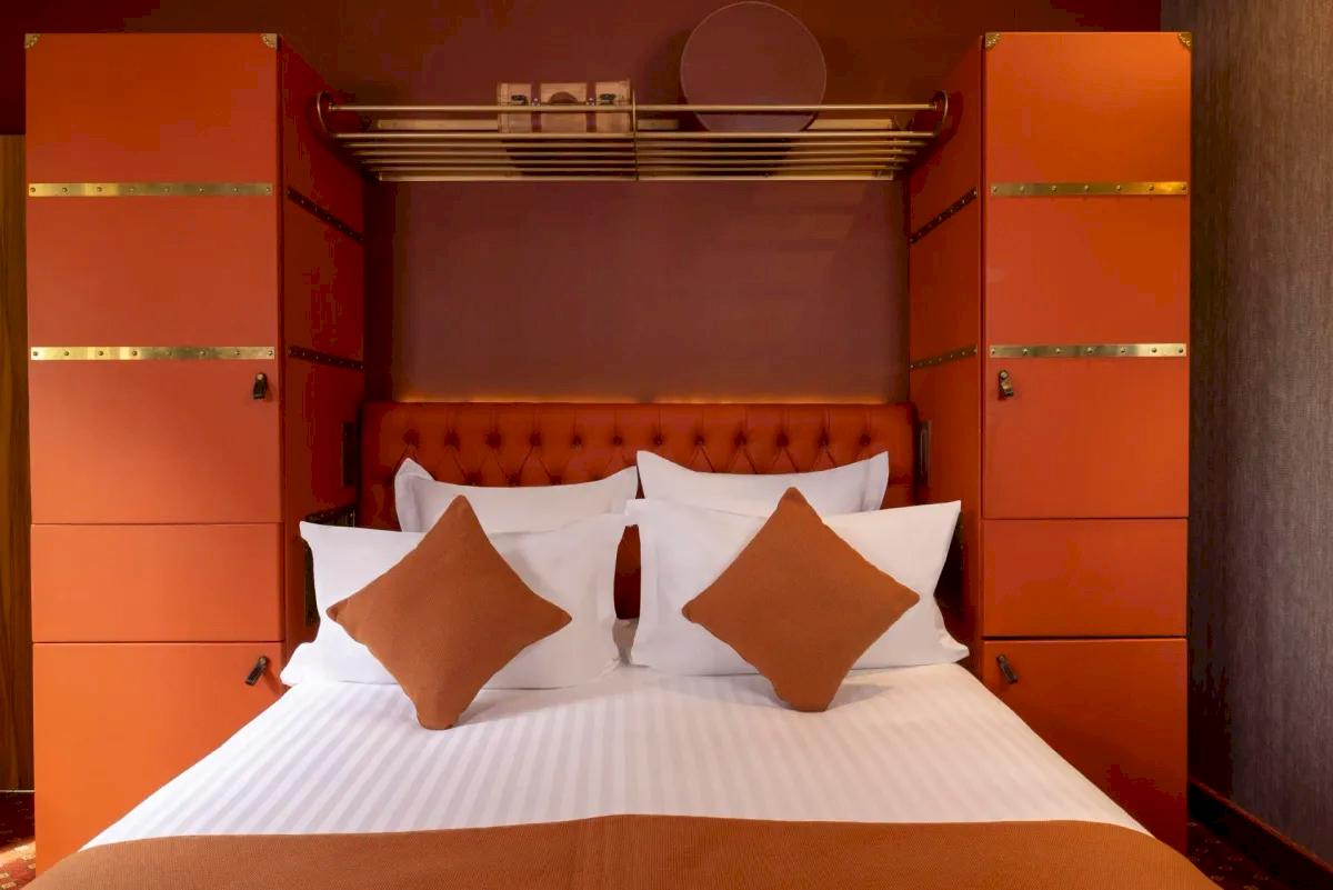 Hotellrum med säng och inredning i orange. 