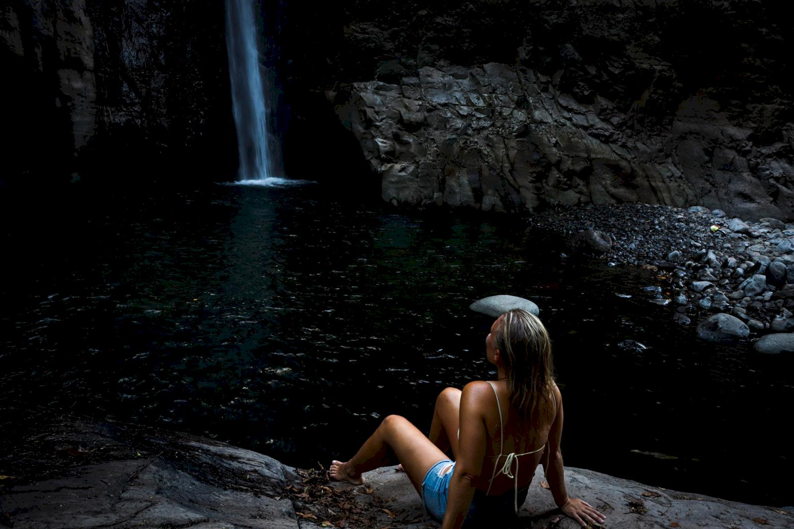 Tjej sitter och tittar på vattenfall. 